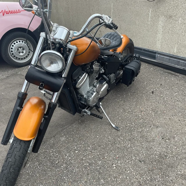 Black leather saddlebag on an orange bobber-style motorcycle